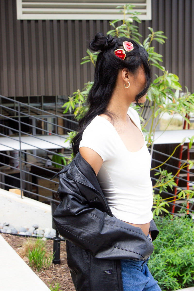 Person wearing a white shirt and black jacket with a plant in the background