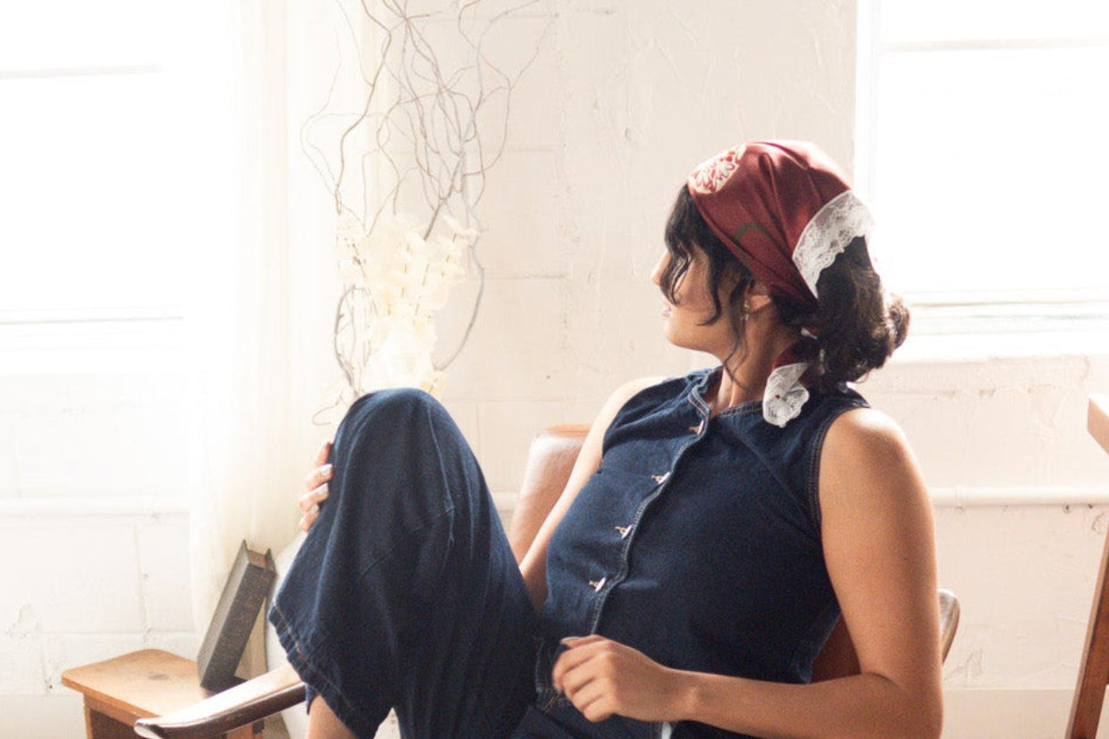 Person sitting on a wooden chair in a room with large windows and a white brick wall.