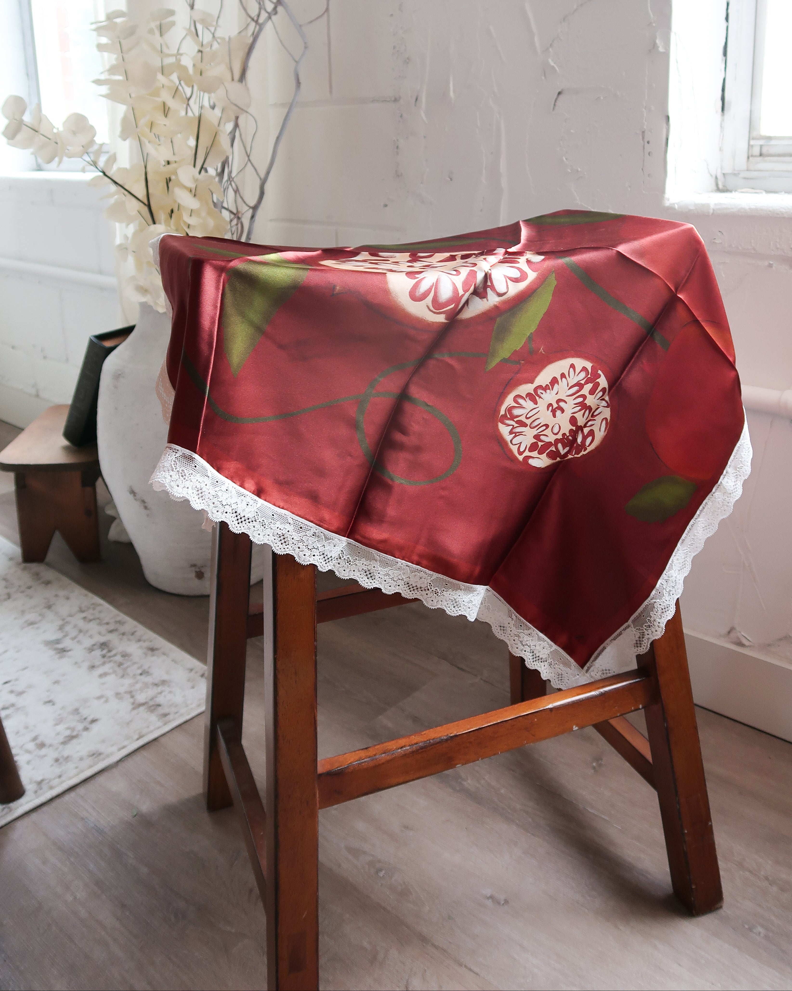 SIlk Scarf with floral design on a wooden chair in a room with white walls and a window.