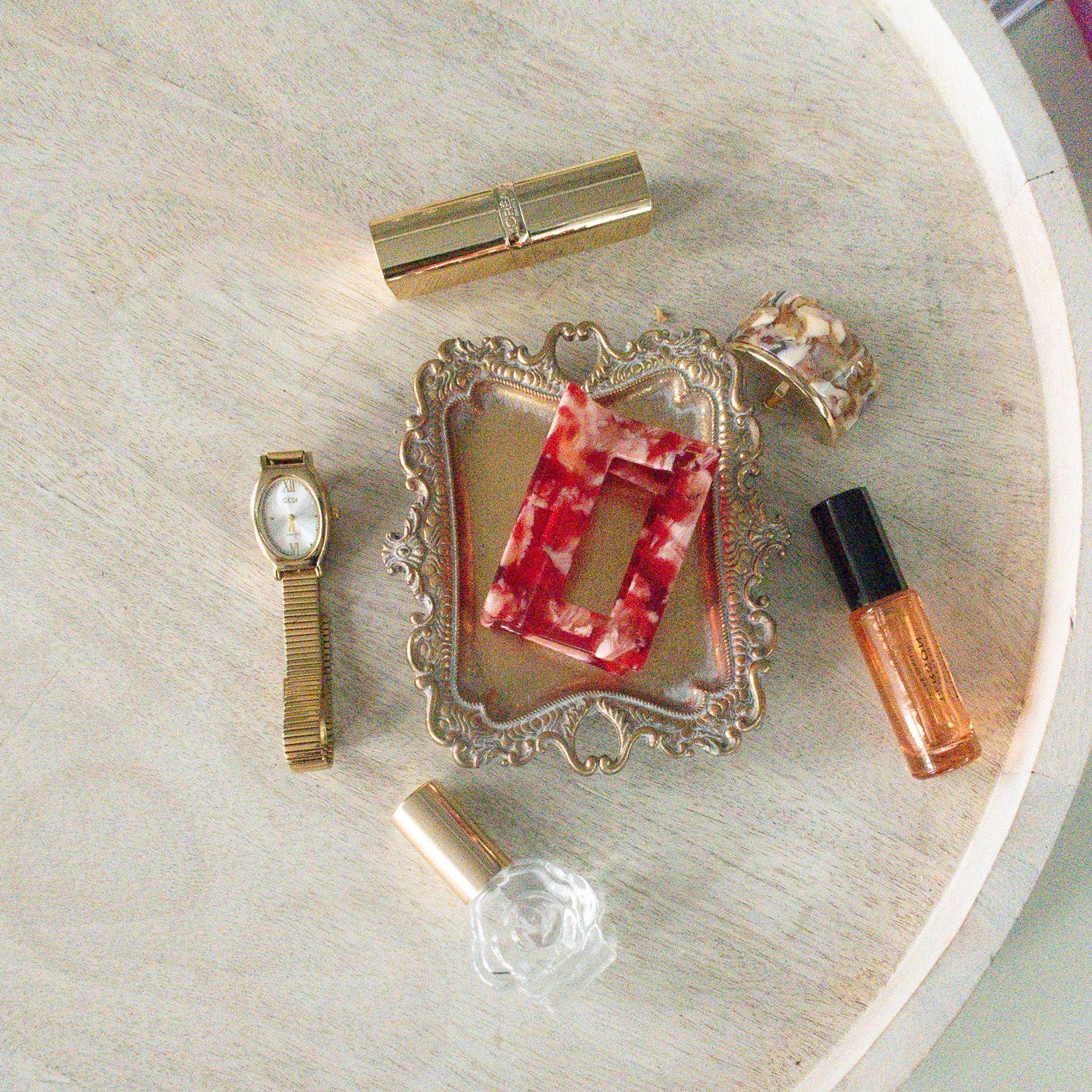 Small decorative items including a watch, perfume bottles, and a framed picture on a round surface.