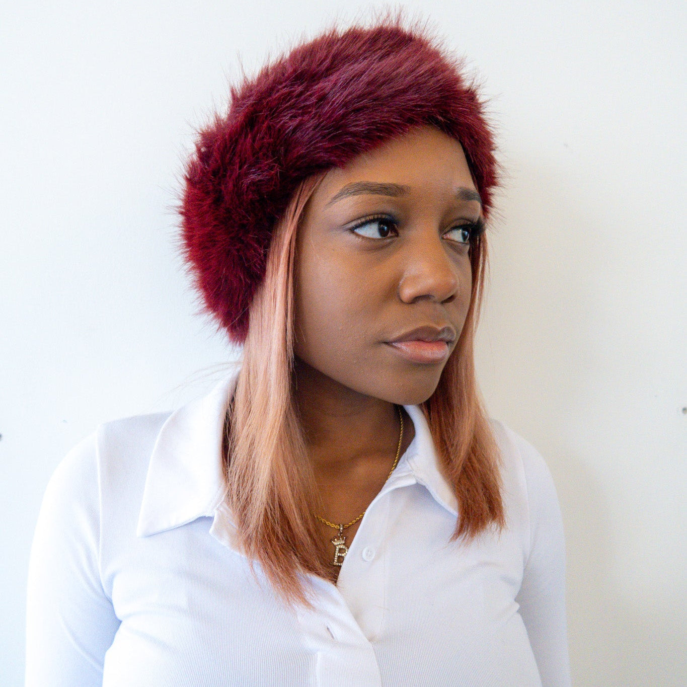 Woman wearing a burgundy fur headband against a white background